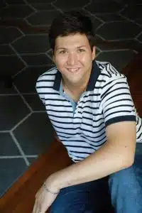 Photo of David Cohen, a man with short dark hair and a striped shirt smiling at the camera