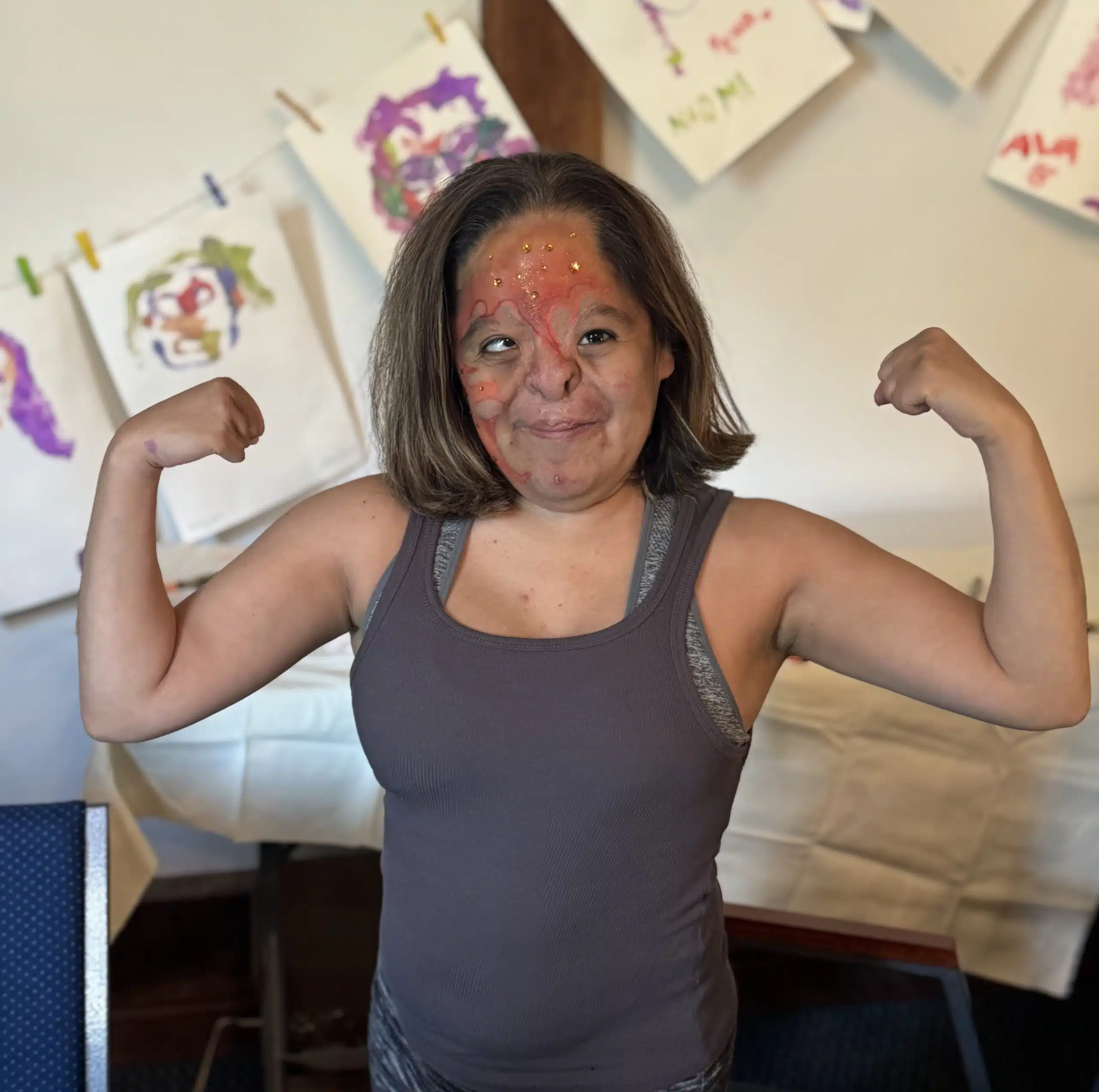 Claudia_IMG_6785 cropped copy claudia flexing in front of paintings of attendee faces