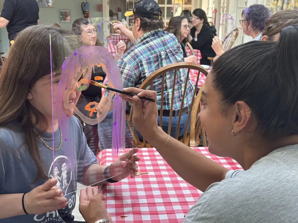 retreat_6 participant painting another participant's face on glass